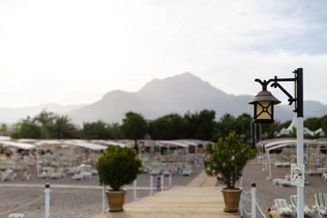 Idyllic view of the wooden pier in the sea with beach and mountain scenery background. Attention tourists-forbidden to jump in water.