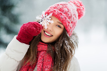 people, season and christmas concept - portrait of happy smiling teenage girl or young woman with snowflake in winter park