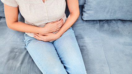 Woman with  stomach issues / problems while sitting on the couch.