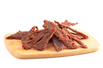 Strips of Beef Jerky on a Wooden Cutting Board Isolated on a White Background