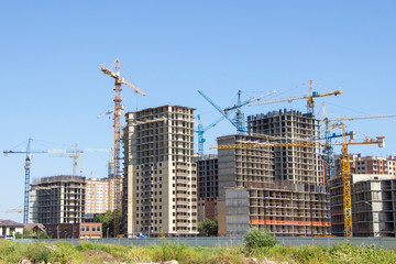 Construction site background. Hoisting cranes and new multi-storey buildings. tower crane and unfinished high-rise building. many cranes