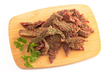 A Pile of Gourmet Cilantro Flavored Beef Jerky on a Wooden Cutting Board