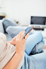 Woman using smart-phone inside the apartment.