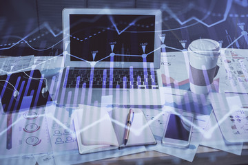 Stock market graph on background with desk and personal computer. Double exposure. Concept of financial analysis.