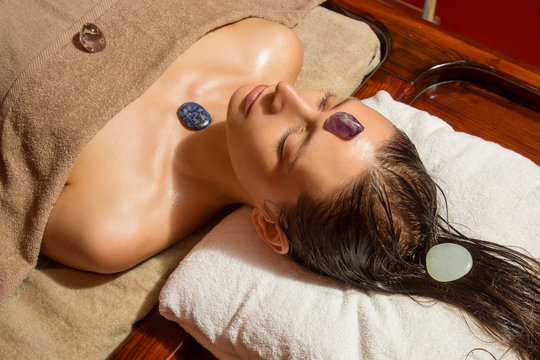 Woman in the spa having energizing crystal massage