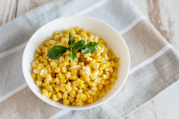 Canned sweet corn in a white bowl on napkin wooden table background.