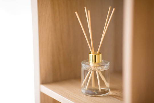 aromatherapy and home perfume concept - aroma reed diffuser on wooden shelf