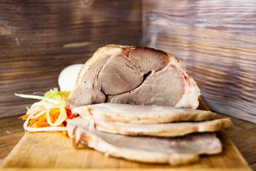 Baked pork ham on a chopping Board with vegetable spaghetti on a rustic wooden table