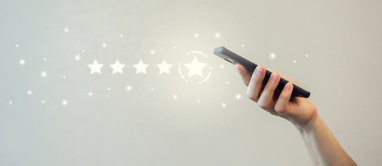 close up on man hand holding smartphone with five star rating feedback to give excellent job...