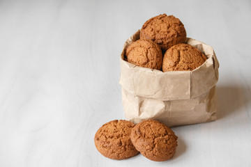 Fresh oatmeal cookies in a bag made of paper on a white table background. Copy, empty space for text