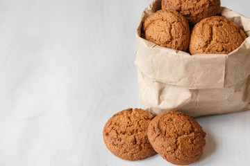 Fresh oatmeal cookies in a bag made of paper on a white table background. Copy, empty space for text