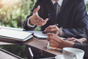 Obraz premium A male business consultant describes a marketing plan to set business strategies for women business owners witch using notebook. business planning and business researching concept.