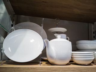 White dishes on a shelf in the store. The concept of choosing dishes, sales, promotions.