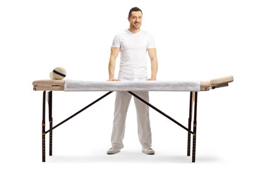 Male masseur standing behind a professional massage bed - obrazy, fototapety, plakaty