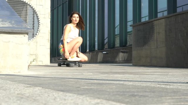 Beautiful modern girl riding a skateboard. Slow motion street riding on a blackboard.