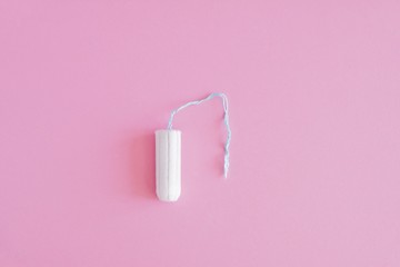 One hygienic tampon on a pink background. Menstrual mothly cycle, means of protection. Top view, flat lay, copy space for text.