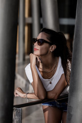 Alluring woman in sunglasses resting while leaning on street handrail
