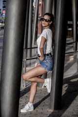 Confident woman in sunglasses leaning on street column