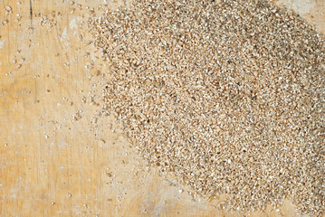 Wheat texture. Crushed grains of wheat cereals on a wooden table. Ground grains scattered on an old plywood board.