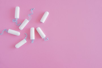 Several white sanitary tampons on a pink background. Menstrual mothly cycle, means of protection....