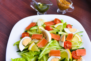 vegetable salad on a white plate. Fresh salad with egg, tomatoes, spinach and avocado on a white wooden background top view. Healthy food.
