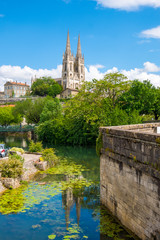 Fototapeta na wymiar Steeples of the Saint-Andre church and view of Niort from the quay of Sevre Niortaise river in France
