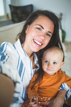 Portrait of cheerful working mother with loving daughter at home