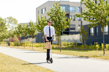 business and people and concept - young businessman with lunch in takeaway paper bag riding electric scooter outdoors