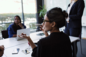 Businesswomen talking with colleagues at conference table