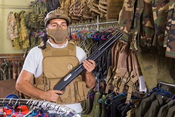 man in army uniform with weapon in military market