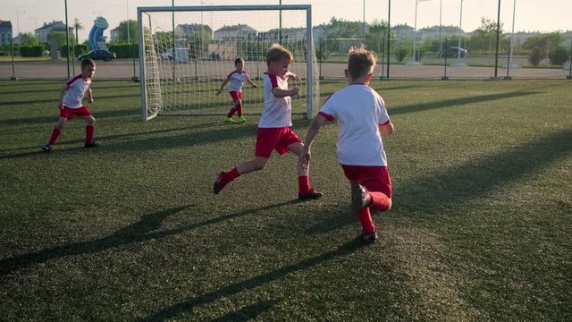 Boy footballer is dribbling ball and kicking goal