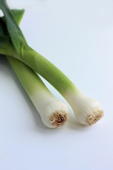 Two green stems of leek, close-up isolated on white background.