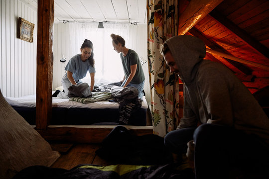 Male and female friends folding blankets in cottage