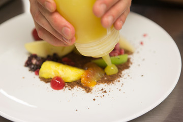 Close up on hands of a chef preparing a gourmet fruit salad dish