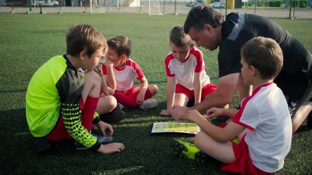 Football team of little boys and trainer are discussing a tactic