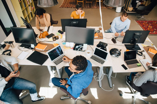 High angle view of business people using technologies while working at desk in office