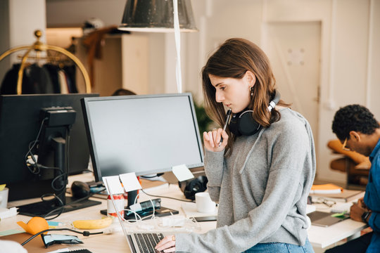 Female computer programmer analyzing data on laptop at desk in office - Powered by Adobe