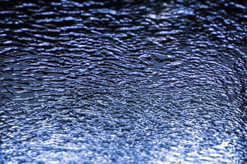 dark blue background with streams of water on the glass while washing a car