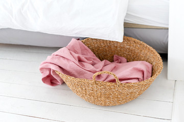 Laundry basket with pink towel. Interior of white stylish room with laundry basket