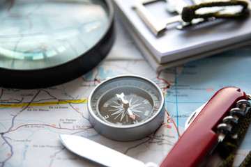 Br&uacute;jula met&aacute;lica, mapa, lupa y otros objetos dispuestos en una mesa
