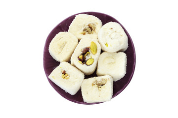 White Turkish delight in purple ceramic plate on isolated white background. Top view of Turkish delight with walnut and peanut.