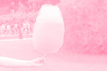 Sweet cotton candy in hand, pink atmospheric background, toned