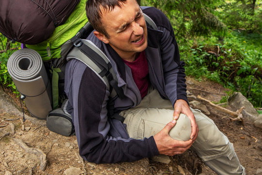 Theme Insurance Company. Man having trouble feeling knee pain during travel in forest. Health problem in journey.