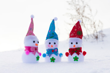 Three toy snowmen in the snow on sunny weather. Good friendly company_