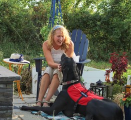 Older adult Caucasian woman with mobility issue is able to enjoy the outdoors on her patio with the help of her loyal and attentive Great Dane service dog by her side
