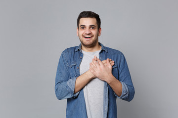 Handsome stylish unshaven young man in denim jeans shirt posing isolated on grey wall background...