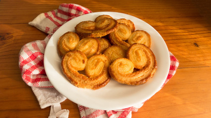 Heart-shaped puff pastry over a white plate and a red cloth on a wooden table   (Gastronomy session).