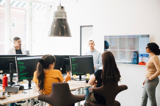 Computer hackers discussing during presentation in office