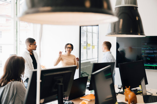 Computer programmers discussing while standing in creative office