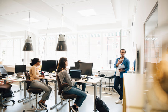 Computer programmer explaining code to colleagues during meeting in creative office